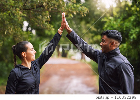 Athletic couple high five while exercising in a park or forest, celebrating and winning before a run. Fit boyfriend and girlfriend bonding while keeping fit and healthy. Fun lovers being active 110352298