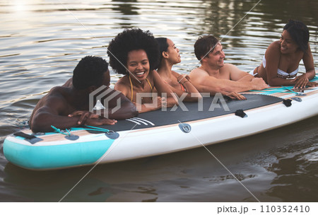 Friends, swimming and summer break with paddle board in a lake, ocean or sea over holiday, vacation or weekend. Diverse group of men and women bonding together, having fun and being playful or social 110352410