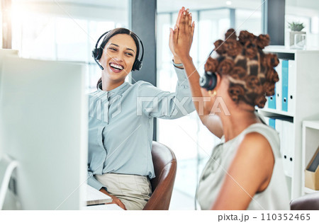 High five, excited and celebrating call center agents with computers happy with a successful deal, promotion and sale. Smiling, cheering and motivated contact us customer service operators in office 110352465