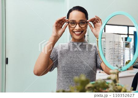 Woman wearing pair of trendy glasses, stylish spectacles and new prescription lenses at an optometrist. Portrait of a customer choosing, buying and shopping for frames for better vision and eyesight Woman wearing pair of trendy glasses, stylish spectacles and new prescription lenses at an optometrist. Portrait of a customer choosing, buying and shopping for frames for better vision and eyesight 110352627