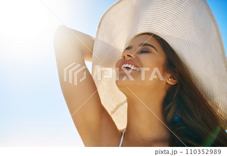 Loving the sun on my skin. Closeup shot of a beautiful young woman spending some time at the beach. 110352989