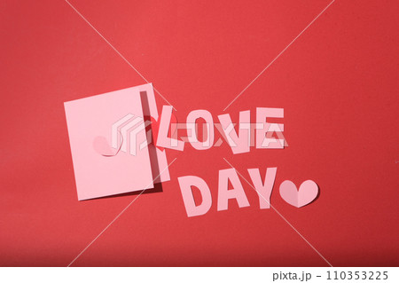 The words LOVE DAY and two pastel pink cards stand out on the red background. Ideal advertising space for Valentine's Day. Flat lay, top view. The words LOVE DAY and two pastel pink cards stand out on the red background. Ideal advertising space for Valentine's Day. Flat lay, top view. 110353225
