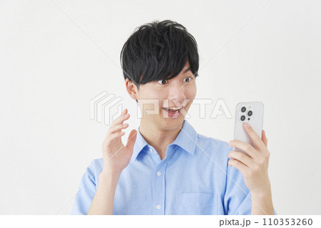 スマートフォンを見て驚く男性 白背景 スマートフォンを見て驚く男性 白背景 110353260