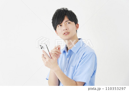 考えながらスマートフォンを持つ男性 白背景 考えながらスマートフォンを持つ男性 白背景 110353297