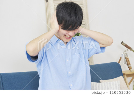 自宅で耳を塞ぐ男性 110353330