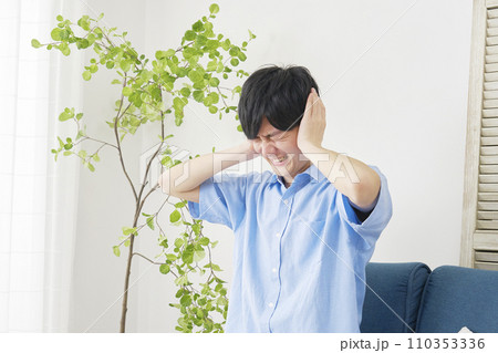 自宅で耳を塞ぐ男性 110353336