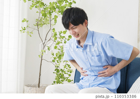 自宅で腹痛がする男性 110353386
