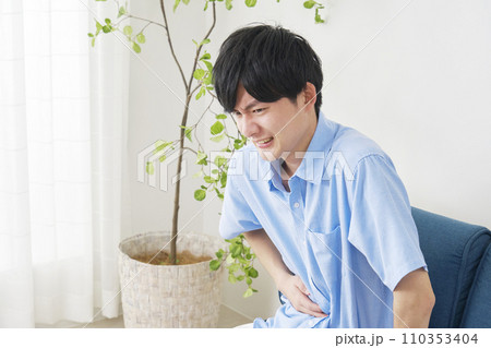 自宅で腹痛がする男性 110353404