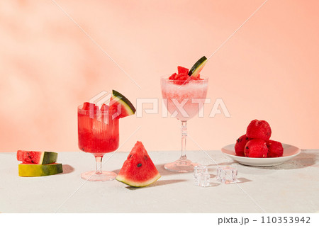 Glass of juice and fresh watermelon displayed on a pastel pink background. Citrulline is an amino acid in watermelon that can effectively relieve muscle soreness. Glass of juice and fresh watermelon displayed on a pastel pink background. Citrulline is an amino acid in watermelon that can effectively relieve muscle soreness. 110353942