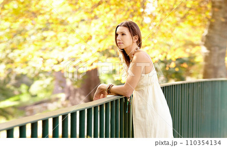 Woman, thinking or park by fence in autumn on holiday vacation in countryside, nature or France, Garden, view or calm female person with peace outdoors for fresh air, wellness or break to relax 110354134