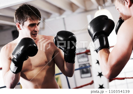 Fight, man and boxer with coaching in gym together for fitness, power strike and training challenge. Strong hit, boxing and athlete in ring with personal trainer, action and confidence in competition Fight, man and boxer with coaching in gym together for fitness, power strike and training challenge. Strong hit, boxing and athlete in ring with personal trainer, action and confidence in competition 110354139