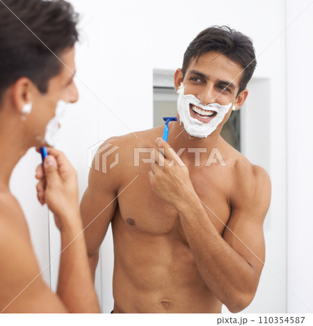 Man, grooming and razor in mirror for hair removal in bathroom, beauty and wellness. Happy male person, skincare and cosmetics or cleaning in morning routine, shaving cream and reflection at home 110354587