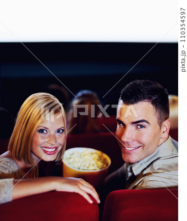 Cinema, portrait of happy couple with popcorn, watching film or eating on romantic night together. Date, man and woman in movie theater with snacks, smile on face and sitting in auditorium to relax. 110354597