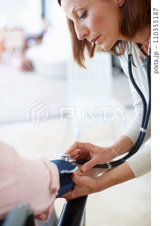 Clinical and professional examination. Closeup of a mature nurse checking the blood pressure of her patient. 110355187