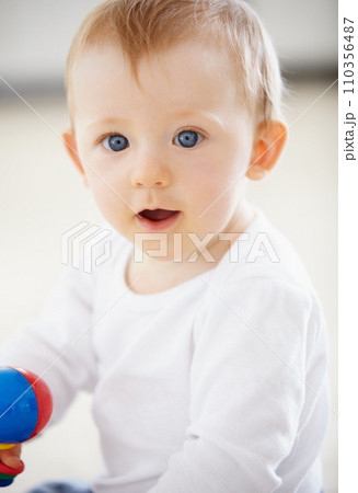 Happy, playing and baby with toys on floor in home for child development, health and growth. Family, youth and closeup of young infant in living room for educational, motor skills and wellness 110356487