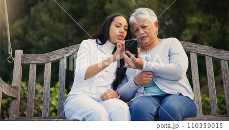 Phone, senior or mother with woman on bench in nature reading news on social media in retirement. Online gossip, mature parent or daughter for together in park or garden as a family with mobile app Phone, senior or mother with woman on bench in nature reading news on social media in retirement. Online gossip, mature parent or daughter for together in park or garden as a family with mobile app 110359015