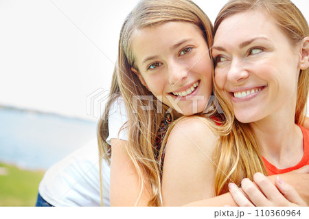 Moms special girl. A happy young daughter embracing her mother while outdoors. 110360964