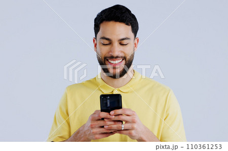 Man, smile and typing with phone in studio, scroll social media and reading notification on white background. Happy indian model download app, mobile games or search contact information on smartphone Man, smile and typing with phone in studio, scroll social media and reading notification on white background. Happy indian model download app, mobile games or search contact information on smartphone 110361253
