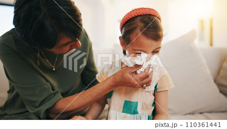 Grandmother, sick kid and sneeze in home living room for allergy, covid or virus on sofa. Grandma, girl child and tissue for cold, flu and bacteria, disease and care or mature woman help blowing nose Grandmother, sick kid and sneeze in home living room for allergy, covid or virus on sofa. Grandma, girl child and tissue for cold, flu and bacteria, disease and care or mature woman help blowing nose 110361441