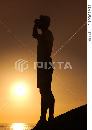 Silhouette, man or looking with hands for view, scenery and wellness on beach with sunset and peace. Person, shadow or adventure and relax for holiday, vacation or experience by ocean or sea with sun Silhouette, man or looking with hands for view, scenery and wellness on beach with sunset and peace. Person, shadow or adventure and relax for holiday, vacation or experience by ocean or sea with sun 110361951