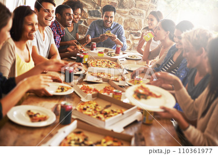 Catching up over great zza. a group of friends enjoying pizza together. 110361977