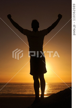 Sunset, beach and silhouette of fitness man with arms up celebration in nature, excited or victory. Energy, shadow and male athlete at the ocean with freedom, achievement or training goal success Sunset, beach and silhouette of fitness man with arms up celebration in nature, excited or victory. Energy, shadow and male athlete at the ocean with freedom, achievement or training goal success 110362089