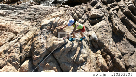Aerial view of woman runner running on sunrise seaside rocks Aerial view of woman runner running on sunrise seaside rocks 110363509