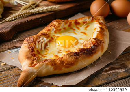 Adjarian khachapuri, delicious Georgian dish in the shape of a boat with cheese, egg and butter, on an old wooden table, gastronomic tourism and travel to popular places, idea for advertising or menu 110363930