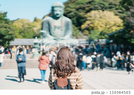 Woman tourist Visiting in Kamakura, Kanagawa, Japan. happy Traveler sightseeing the Great Buddha statue. Landmark and popular for tourists attraction near Tokyo. Travel and Vacation concept Woman tourist Visiting in Kamakura, Kanagawa, Japan. happy Traveler sightseeing the Great Buddha statue. Landmark and popular for tourists attraction near Tokyo. Travel and Vacation concept 110364503