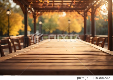 Empty wooden table top with illuminated wooden pergola in park background with bokeh autumn sunlight. 110366282