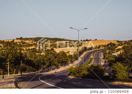 Highway curve road overpass nature landscape background dark tone mist day time street tall lanterns trees bushes sideway 110366409