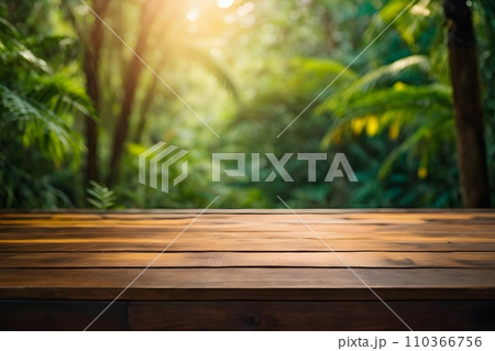 Empty wooden table top with blur jungle background with bokeh light. Empty wooden table top with blur jungle background with bokeh light. 110366756
