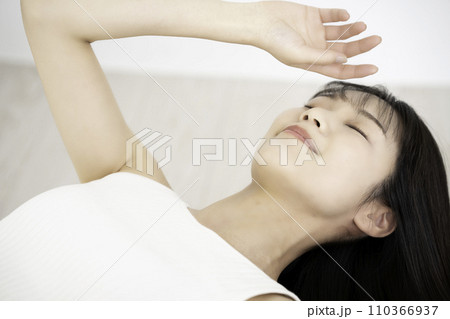 寝転んでくつろぐタンクトップの若い女性 110366937