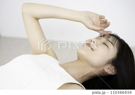 寝転んでくつろぐタンクトップの若い女性 110366939