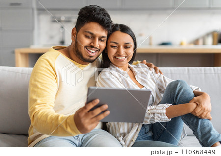 Happy Indian Couple Watching Videos On Digital Tablet While Relaxing At Home 110368449