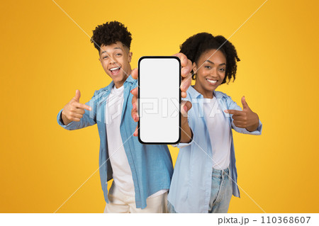 Happy confident young african american man and woman in casual point fingers at smartphone 110368607