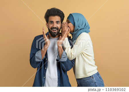 Gossips Concept. Muslim Woman In Hijab Whispering Secret To Her Surprised Boyfriend 110369102