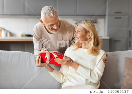 Grey-haired man husband greeting his beautiful wife with Valentine Day Grey-haired man husband greeting his beautiful wife with Valentine Day 110369157