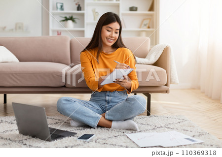 Happy millennial asian woman studying at home Happy millennial asian woman studying at home 110369318