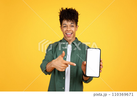 Positive african american guy pointing at phone with white screen Positive african american guy pointing at phone with white screen 110369671