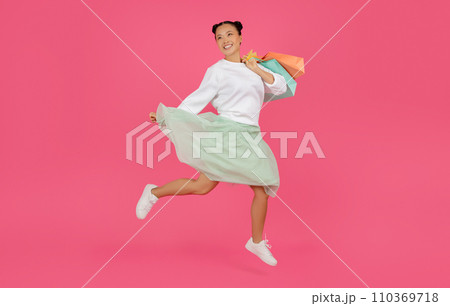 Happy asian woman jumping high with shopping bags in her hands 110369718