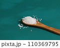Coarse salt crystals on a blue table. Wooden spoon 110369795