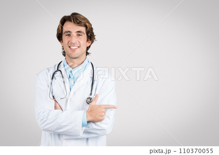 Smiling doctor pointing to the side, stethoscope visible Smiling doctor pointing to the side, stethoscope visible 110370055