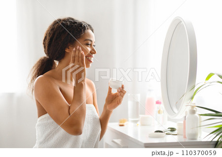 Attractive Young African American Woman Applying Nourishing Cream On Face 110370059