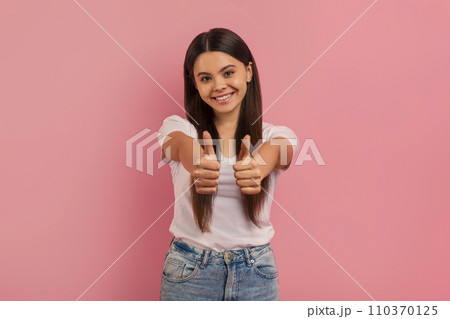 Happy teenage girl giving two enthusiastic thumbs up at camera 110370125