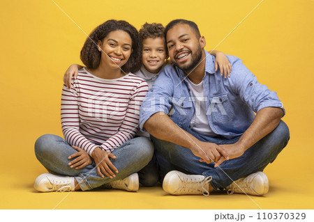 Happy african american family of three sitting on floor and embracing Happy african american family of three sitting on floor and embracing 110370329