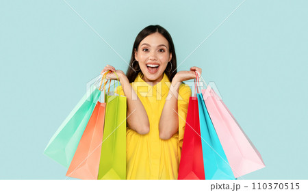 Emotional brunette woman showing colorful shopping bags Emotional brunette woman showing colorful shopping bags 110370515
