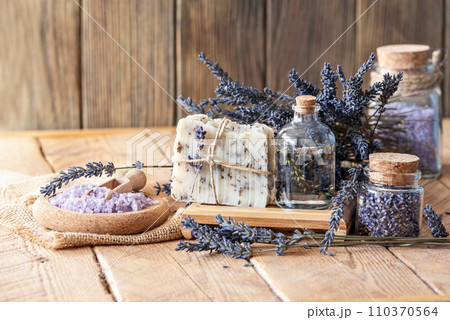 Wellness treatments with lavender flowers on wooden table. Spa still-life. Essential oils, sea salt, towels and handmade soap. Natural herb cosmetic with lavender flowers 110370564