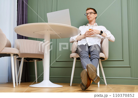 Middle aged man relaxing in front of laptop 110370852