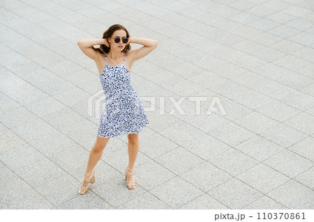 Top view of woman in sundress and sunglasses holding hands behind her head 110370861